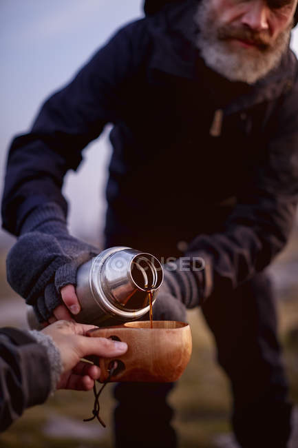 Hiker pouring coffee into friends cup — Stock Photo