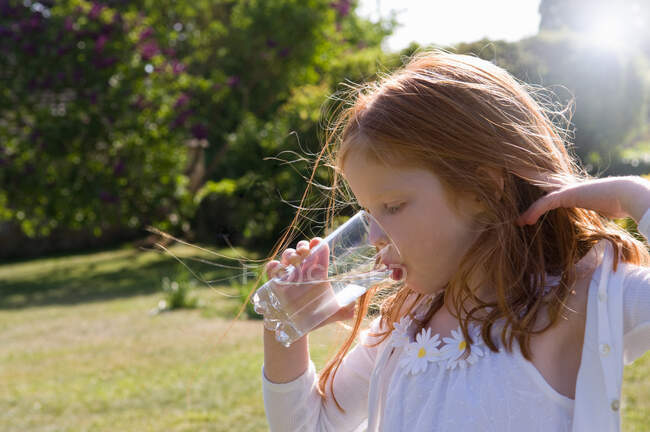 Fille boire un verre d'eau dans la cour — Photo de stock