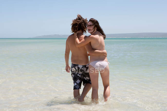 Casal caminhando na água na praia — Fotografia de Stock