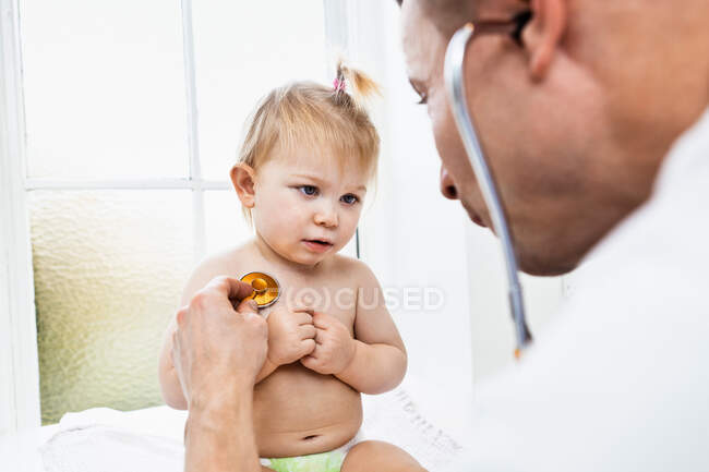 Medico esaminando bambina con stetoscopio — Foto stock