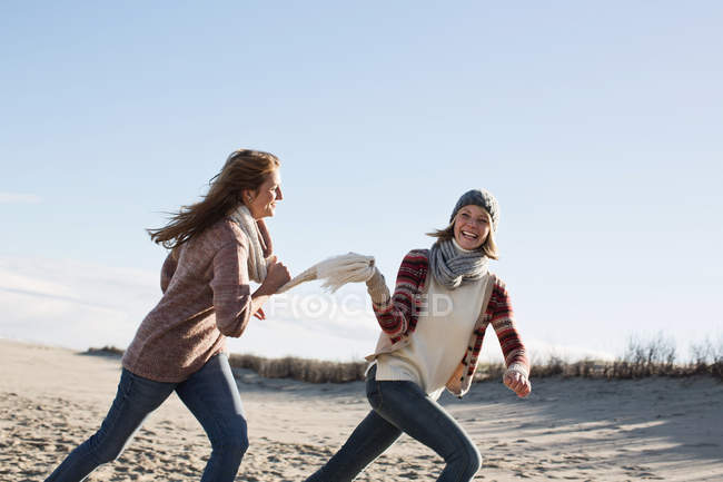 Mulheres sorridentes correndo na praia — Fotografia de Stock