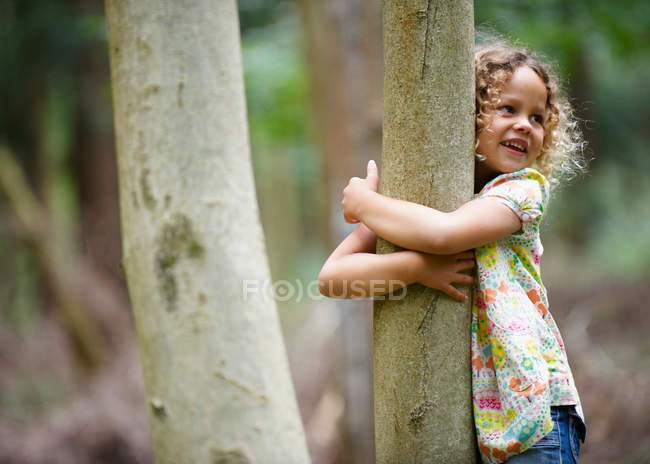 Junges Mädchen umarmt lächelnd Baum — Stockfoto
