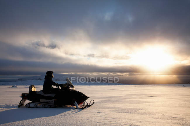 Mann fährt Schneemobil in verschneites Feld — Stockfoto