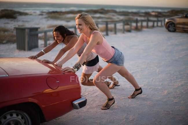 Chicas empujando su coche roto - foto de stock