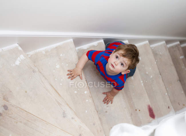 Niño pequeño escalando escalones - foto de stock