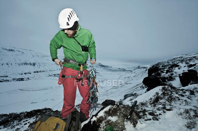 Альпинист с карабинами на снежном холме — стоковое фото