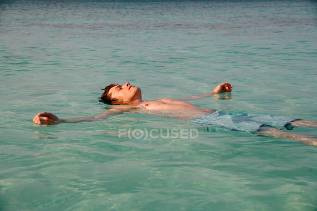 Hombre flotando en aguas tropicales - foto de stock
