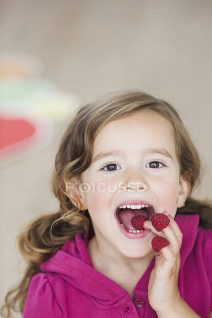 Young girl eating berries from fingers — Stock Photo