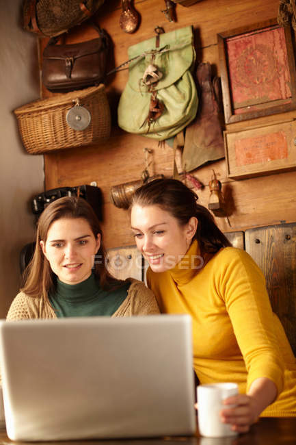Femmes utilisant un ordinateur portable dans un café, se concentrer sur l'avant-plan — Photo de stock