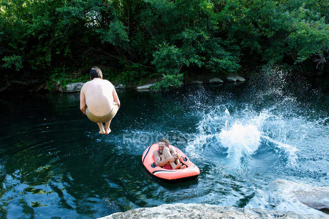 Hombres saltando en el lago del bosque - foto de stock