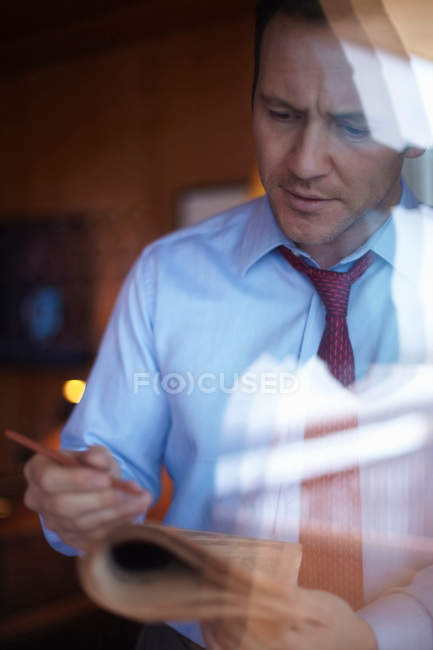 Empresário lendo jornal na janela — Fotografia de Stock