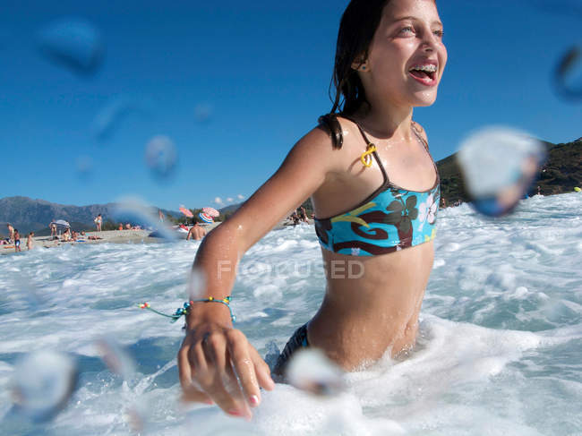 Chica en la playa, nadando en el mar - foto de stock