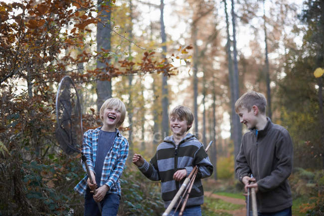 Niños caminando por el bosque con equipo de pesca - foto de stock