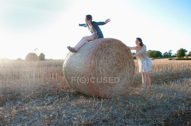 Junge Frauen spielen auf Heuballen im Feld — Stockfoto