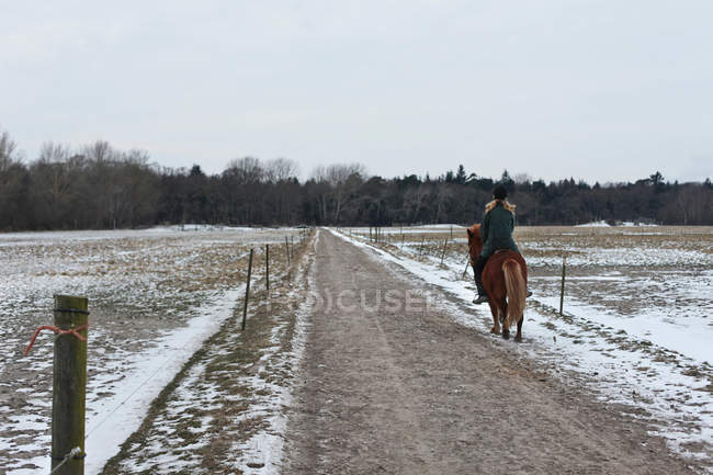 Femme à cheval sur le chemin enneigé — Photo de stock