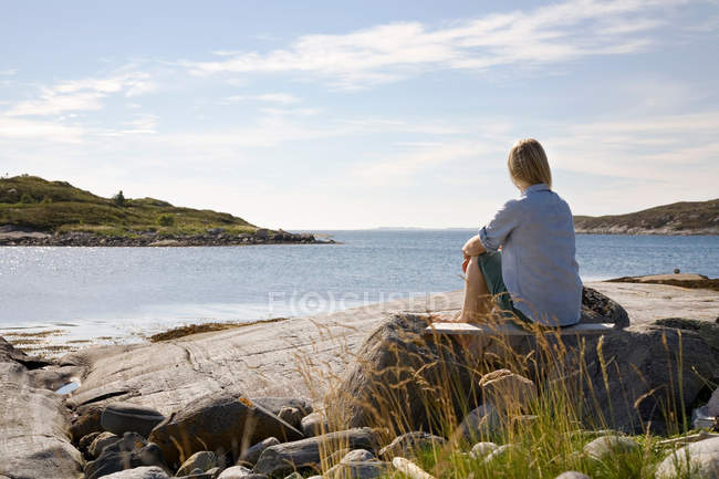 Mujer sentada y mirando al mar - foto de stock