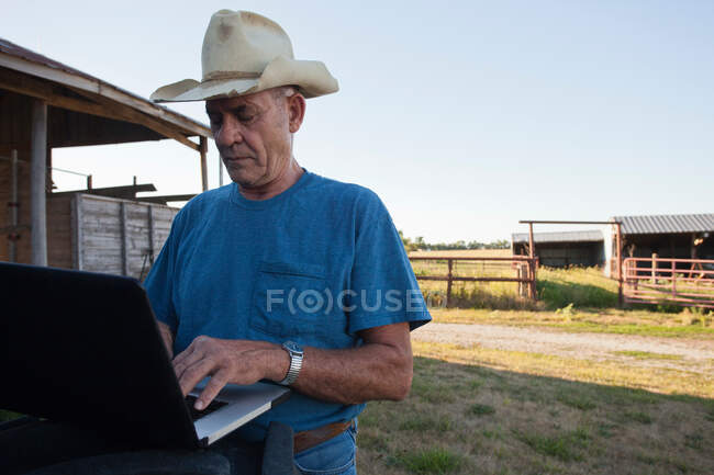 Farmer using laptop by barn — Stock Photo