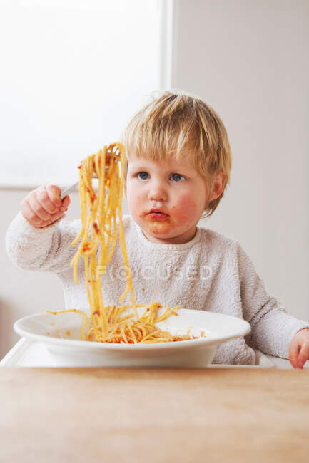 Грязный мальчик ест спагетти — стоковое фото