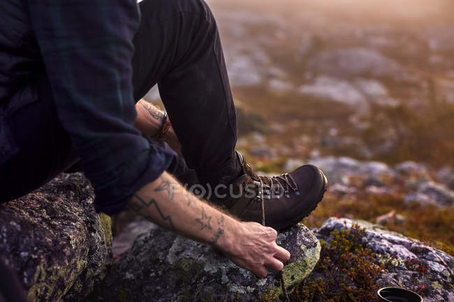 Imagem cortada do homem amarrando cadarços nas montanhas — Fotografia de Stock