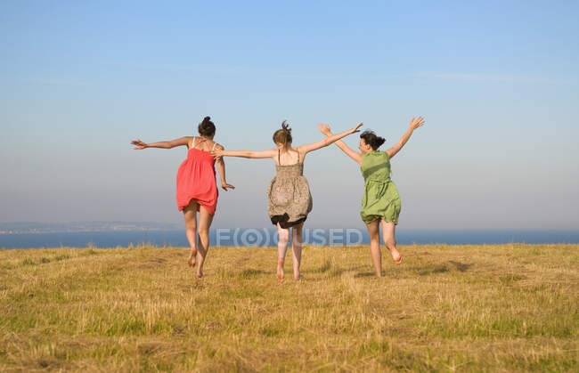 Girls dancing on grassy cliff top — Stock Photo