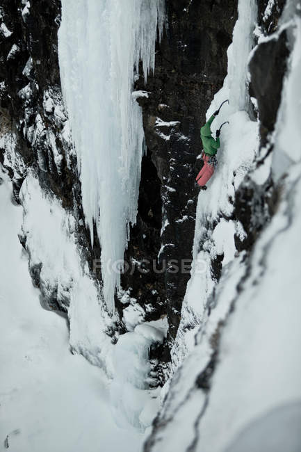 Escalador com picaretas descendo colina nevada — Fotografia de Stock