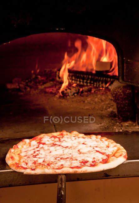 Chef pulling pizza from oven — Stock Photo