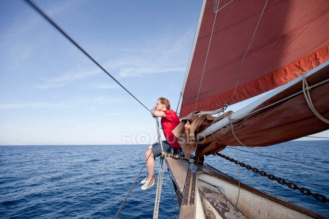 Hombre sentado en la proa de un barco - foto de stock
