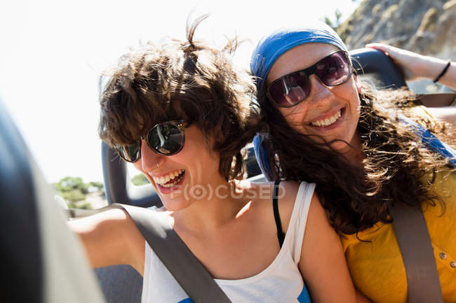 Mujeres sonriendo juntas en convertible - foto de stock