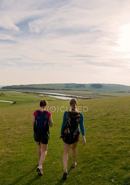 Vista trasera de mujeres excursionistas caminando hacia el río - foto de stock