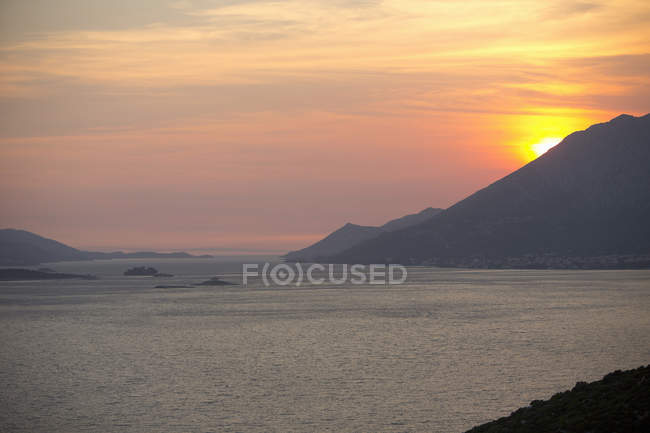 Puesta de sol sobre las montañas y el mar - foto de stock