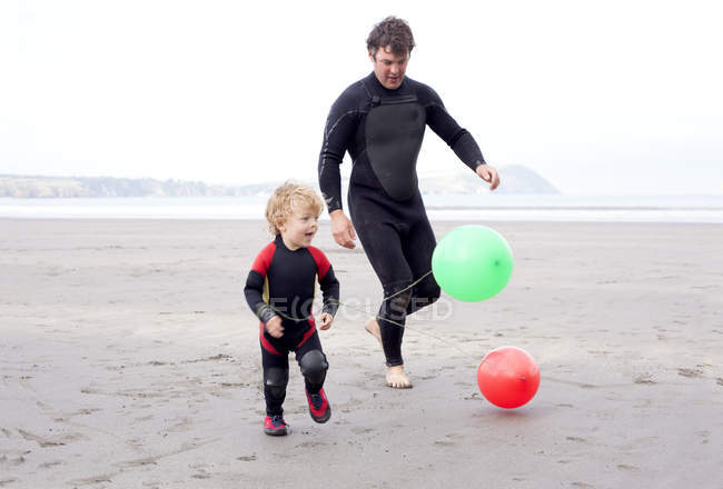 Father and son playing with balloons on beach — Stock Photo