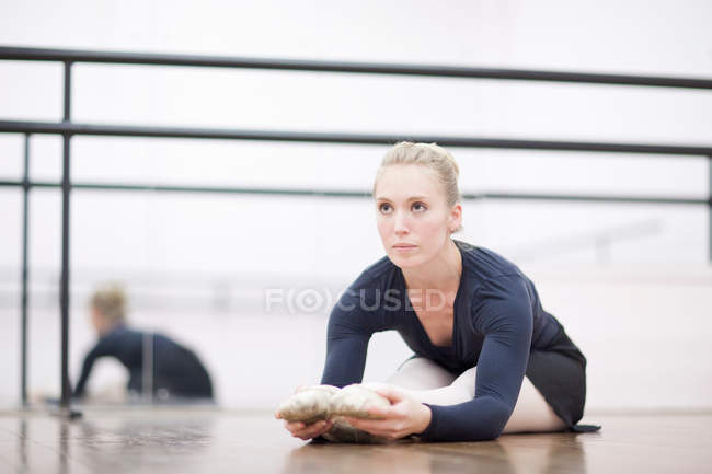 Балерина растягивается на полу — стоковое фото
