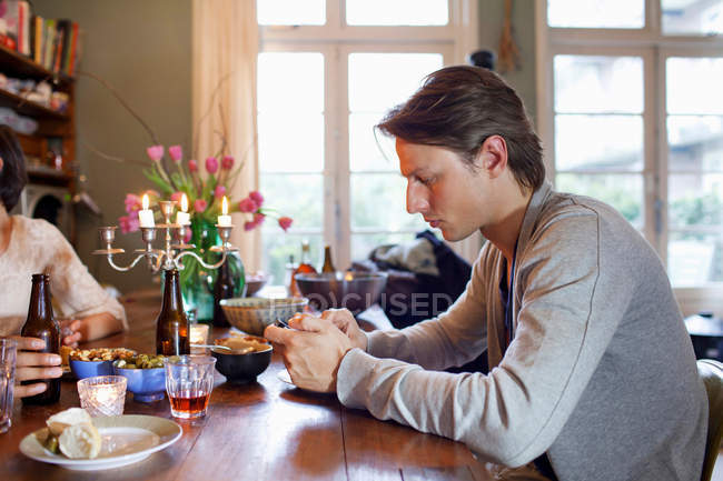 Homem usando telefone celular na mesa de jantar — Fotografia de Stock