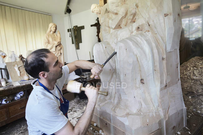 Sculptor chiseling figure from wood — Stock Photo