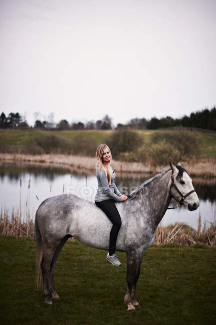 Menina sentada no cavalo no campo — Fotografia de Stock