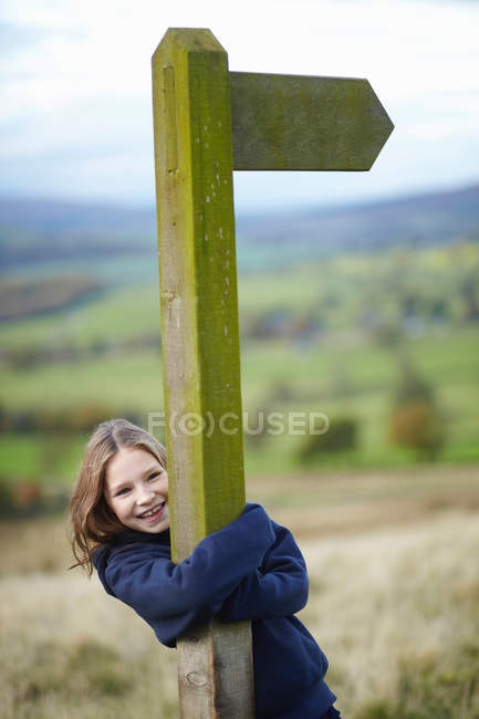 Sorridente ragazza abbracciando cartello stradale — Foto stock