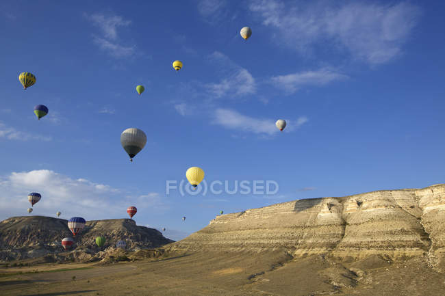 Hot air balloons floating into distance over mountains — Stock Photo