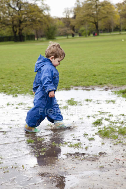 Bambino ragazzo a piedi in pozzanghera — Foto stock