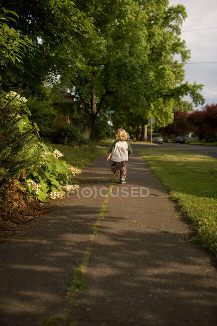 Toddler boy walking along sidewalk — Stock Photo