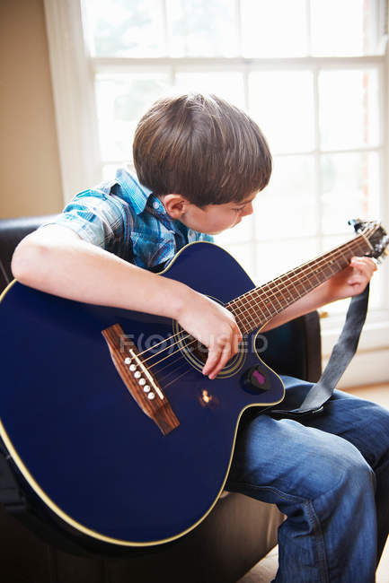 Junge spielt Gitarre auf Sofa — Stockfoto