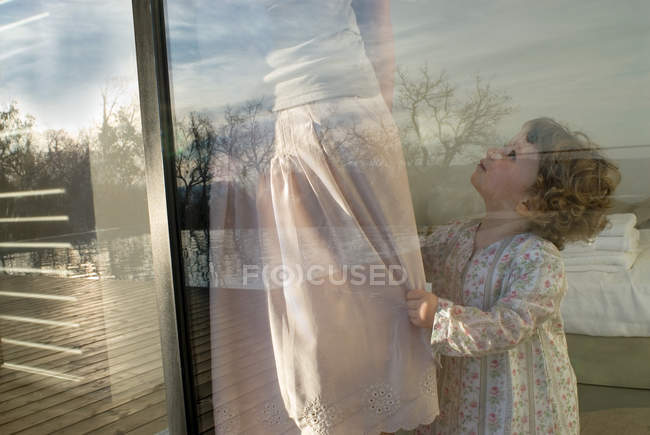 Mother and daughter in bedroom at window with reflection, child looking at mom — Stock Photo