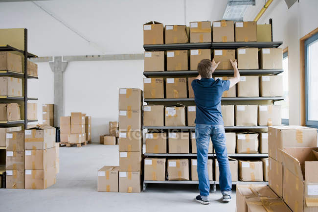 Hombre archivando cajas de cartón en el almacenamiento - foto de stock