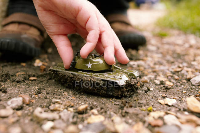 Mão brincando com tanque de brinquedo na sujeira — Fotografia de Stock