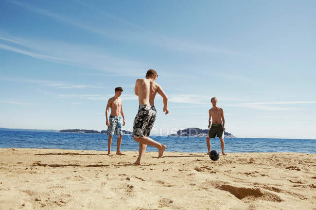 Uomini che giocano a calcio sulla spiaggia — Foto stock
