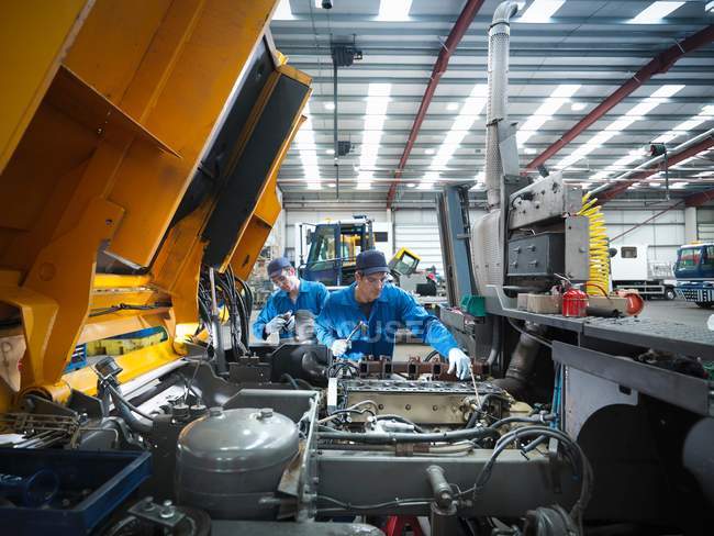 Ingenieros de reparación de motores en la fábrica de reparación de camiones - foto de stock