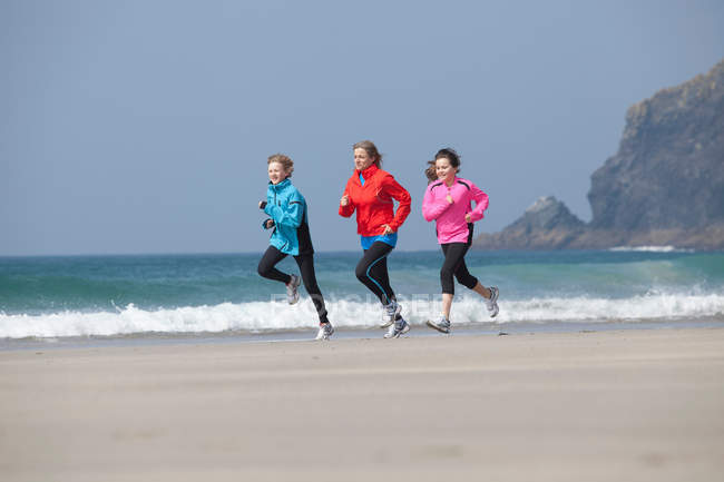 Семья, бегающая вместе на пляже — стоковое фото