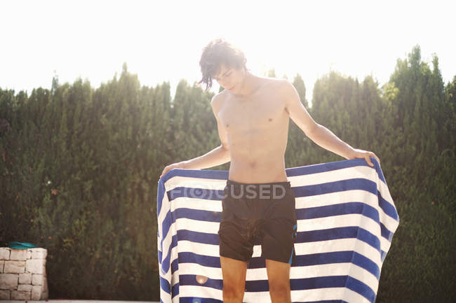 Giovane uomo asciugandosi con asciugamano a bordo piscina — Foto stock