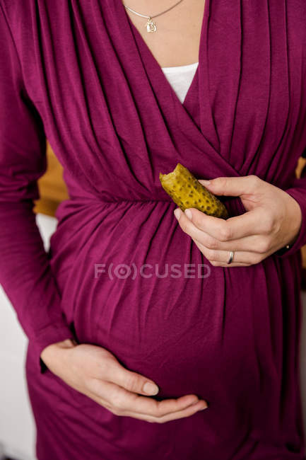 Pregnant woman eating pickle — Stock Photo