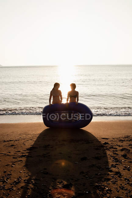 Женщины с надувной лодкой на пляже — стоковое фото
