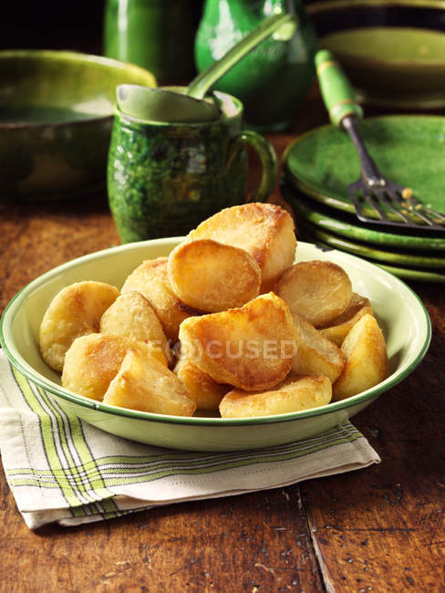 Batatas roastes em tigela verde vintage em guardanapo de pano — Fotografia de Stock